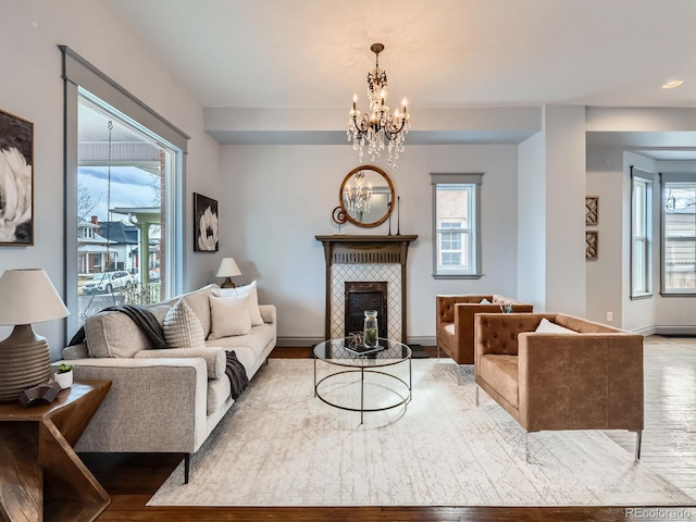 living area with a chandelier, wood finished floors, and a healthy amount of sunlight