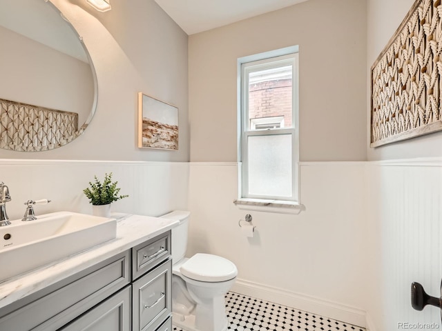 bathroom with a wainscoted wall, vanity, and toilet