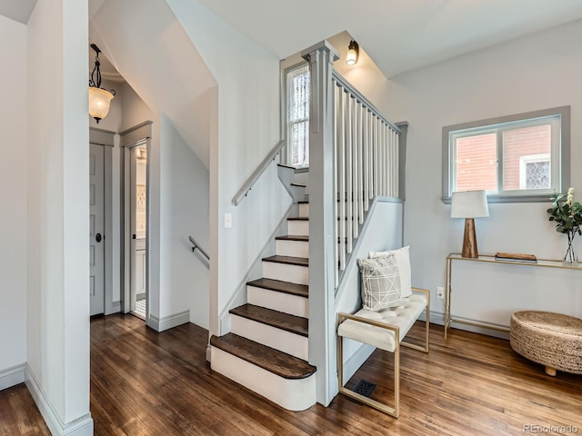 staircase featuring a healthy amount of sunlight, baseboards, and hardwood / wood-style flooring