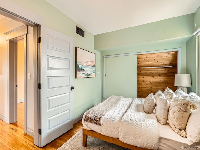 bedroom with baseboards, a closet, visible vents, and light wood-style floors