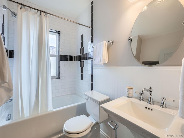 full bathroom with toilet, a wainscoted wall, a sink, and shower / tub combo with curtain