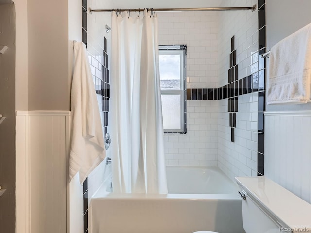 full bath with toilet, a wainscoted wall, and shower / tub combo with curtain