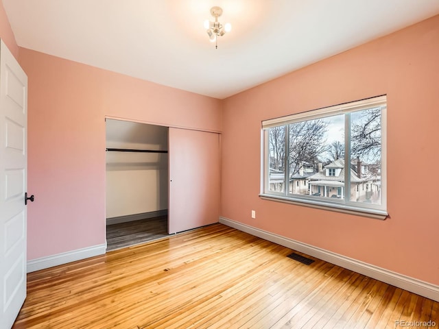 unfurnished bedroom with light wood-style floors, a closet, visible vents, and baseboards