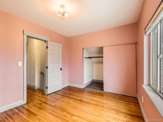 unfurnished bedroom with a closet, light wood-type flooring, and baseboards