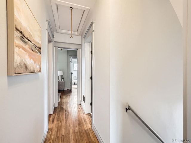 corridor with an upstairs landing, wood finished floors, attic access, and baseboards