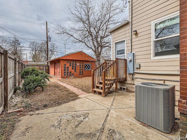 view of patio with cooling unit, a fenced backyard, and an outbuilding