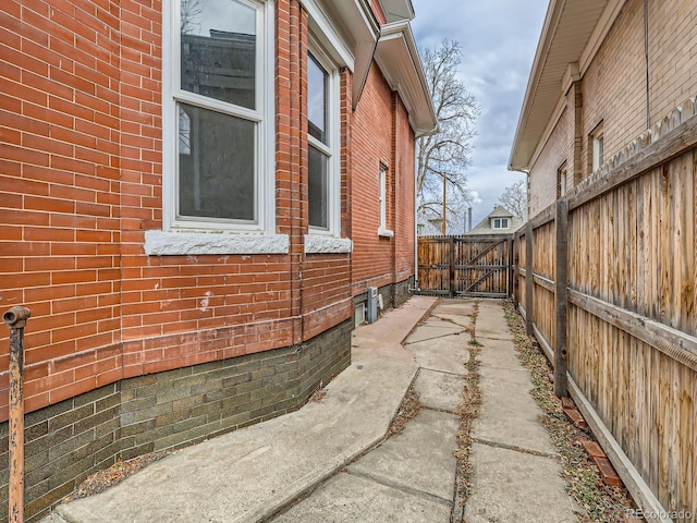 view of side of property featuring a gate, brick siding, and fence