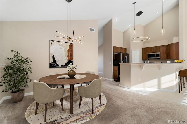 dining room featuring light carpet, high vaulted ceiling, and a chandelier