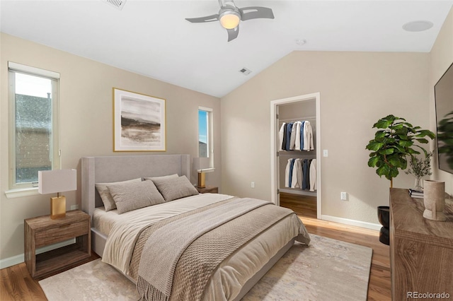 bedroom with ceiling fan, lofted ceiling, a spacious closet, and light wood-type flooring