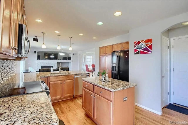 16893 Trail View Cir, Parker, CO 80134 - kitchen with appliances with stainless steel finishes, a sink, a glass covered fireplace, light wood-style floors, and recessed lighting