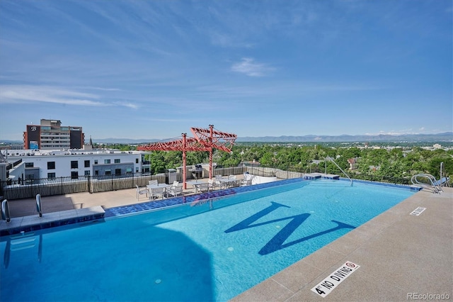 view of swimming pool featuring a patio area, fence, and a mountain view