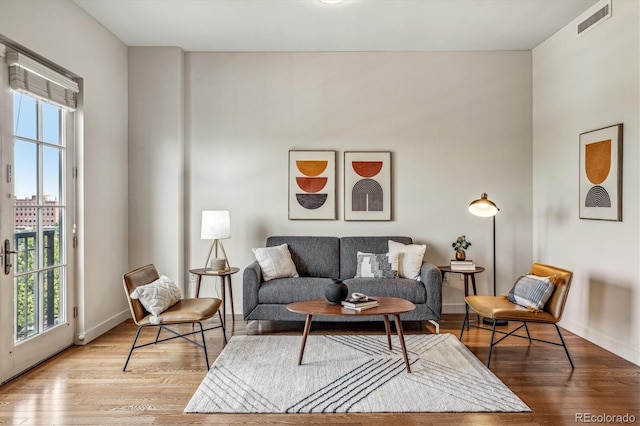 living area with visible vents, plenty of natural light, baseboards, and wood finished floors