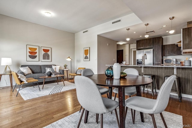 dining area with light wood-style floors, visible vents, and baseboards