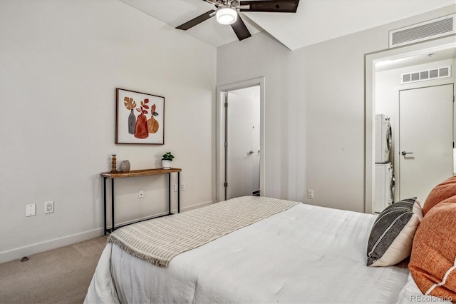 carpeted bedroom featuring visible vents, baseboards, a ceiling fan, and stacked washer / dryer