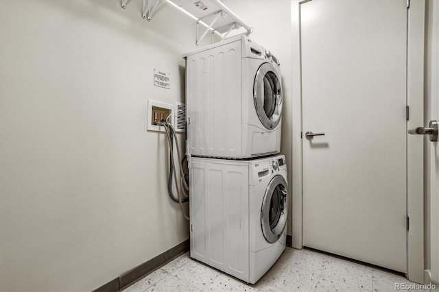 laundry room with laundry area, baseboards, stacked washer / drying machine, and light floors