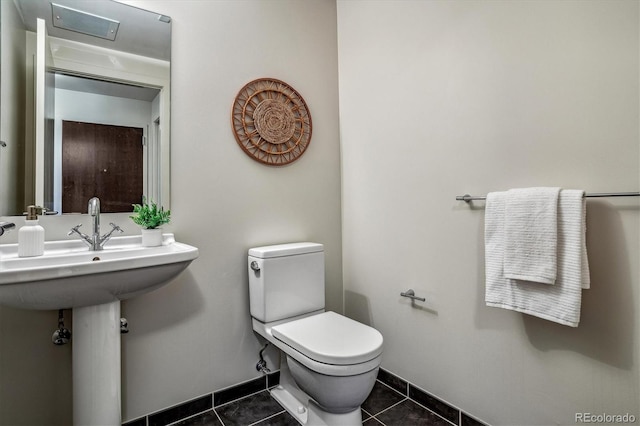 half bath featuring baseboards, toilet, and tile patterned flooring