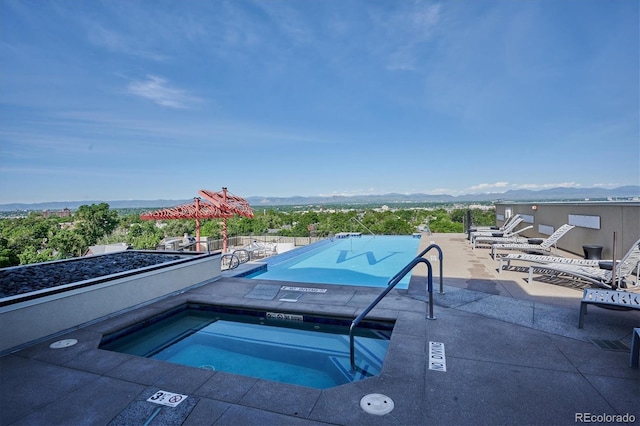 pool with a mountain view, a hot tub, and a patio