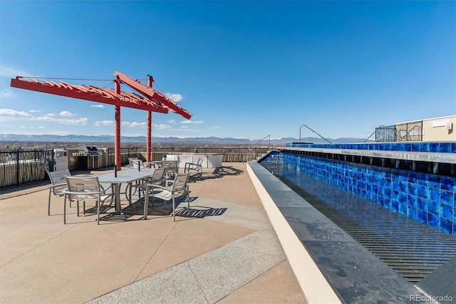 view of patio with outdoor dining area, fence, and a mountain view