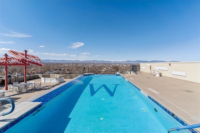 community pool featuring a mountain view, fence, and a patio area