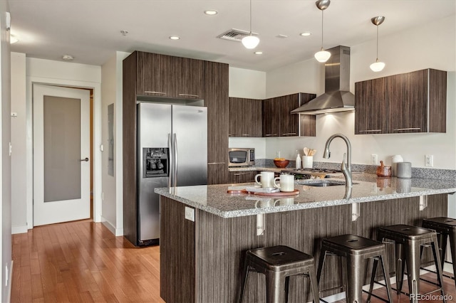 410 Acoma St Unit 518, Denver, CO 80204 - kitchen featuring stainless steel appliances, wall chimney exhaust hood, a sink, a peninsula, and a kitchen breakfast bar