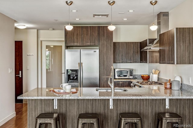 410 Acoma St Unit 518, Denver, CO 80204 - kitchen with stainless steel appliances, a peninsula, light stone counters, dark wood-style flooring, and hanging light fixtures