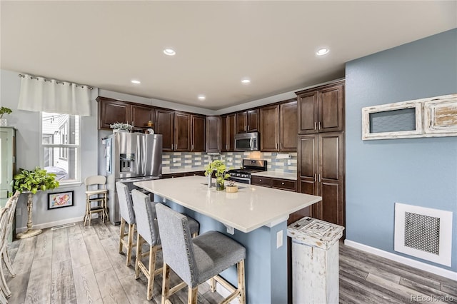 3944 Trail Stone Cir, Castle Rock, CO 80108 - kitchen with stainless steel appliances, a kitchen breakfast bar, light countertops, decorative backsplash, and dark brown cabinets