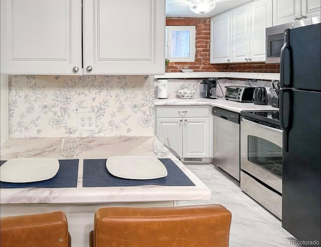 1351 N Franklin St, Denver, CO 80218 - kitchen featuring stainless steel appliances, white cabinetry, light marble finish flooring, and light countertops