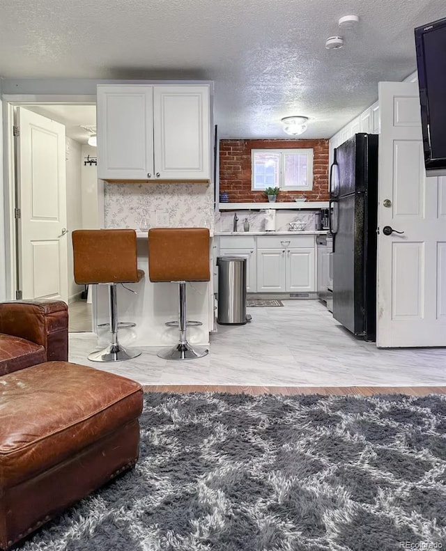 1351 N Franklin St, Denver, CO 80218 - kitchen featuring freestanding refrigerator, white cabinetry, and a textured ceiling
