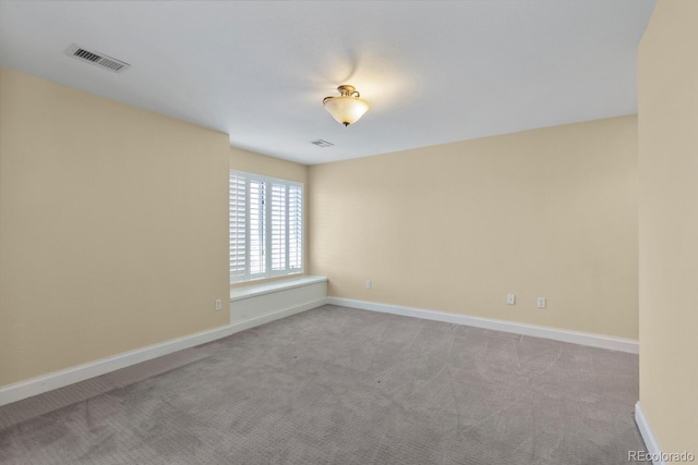 carpeted spare room featuring baseboards and visible vents