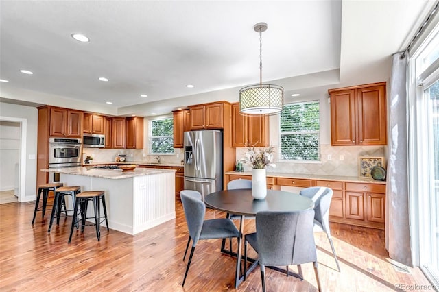 10646 Amesbury Way, Highlands Ranch, CO 80126 - kitchen featuring appliances with stainless steel finishes, recessed lighting, a center island, tasteful backsplash, and a breakfast bar area