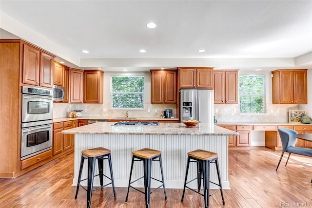 10646 Amesbury Way, Highlands Ranch, CO 80126 - kitchen with stainless steel appliances, a breakfast bar, a kitchen island, light wood-style floors, and recessed lighting