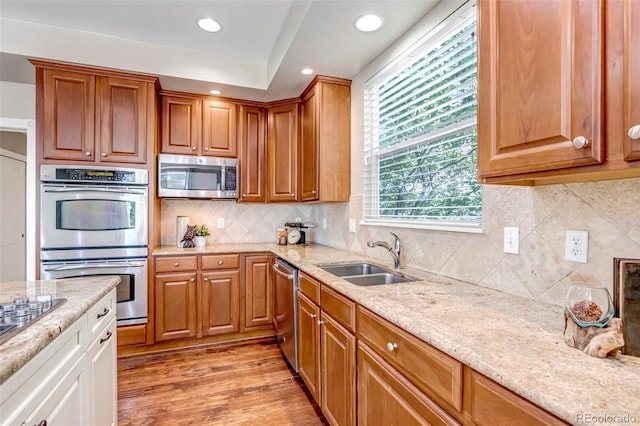 10646 Amesbury Way, Highlands Ranch, CO 80126 - kitchen with appliances with stainless steel finishes, light stone countertops, light wood-style floors, recessed lighting, and brown cabinets