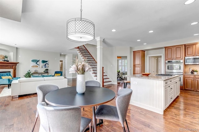 10646 Amesbury Way, Highlands Ranch, CO 80126 - dining space featuring stairway, recessed lighting, light wood-type flooring, and a glass covered fireplace