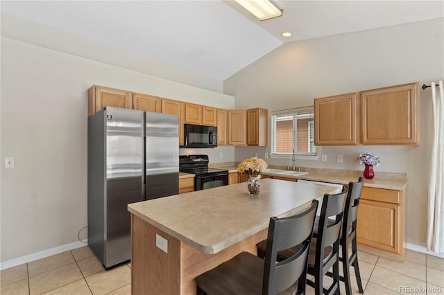 kitchen featuring light tile patterned floors, a kitchen breakfast bar, black appliances, a kitchen island, and vaulted ceiling