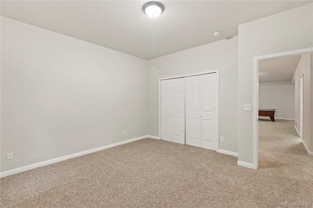 unfurnished bedroom featuring light carpet, a closet, and a textured ceiling