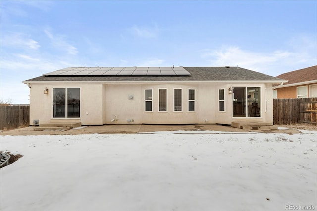 snow covered house featuring solar panels