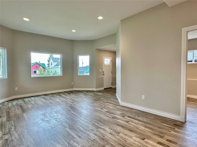 unfurnished room featuring recessed lighting, wood finished floors, and baseboards