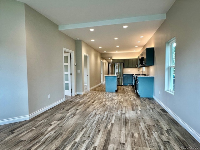 kitchen with wood finished floors, baseboards, recessed lighting, appliances with stainless steel finishes, and open floor plan