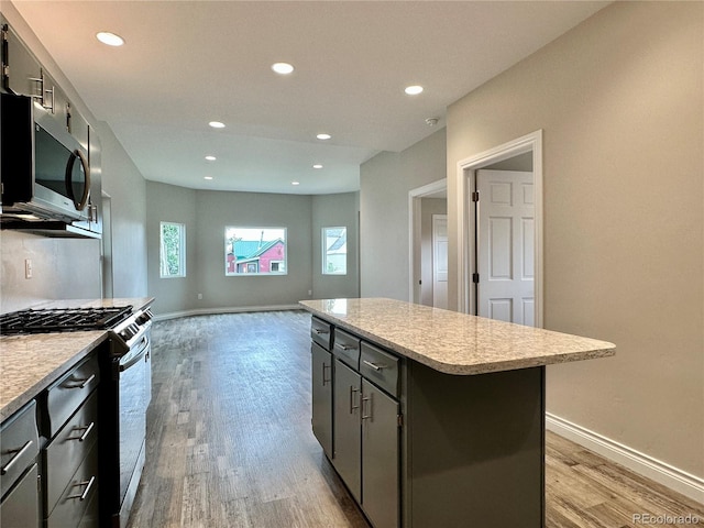 kitchen featuring baseboards, recessed lighting, stainless steel appliances, light wood-type flooring, and a center island