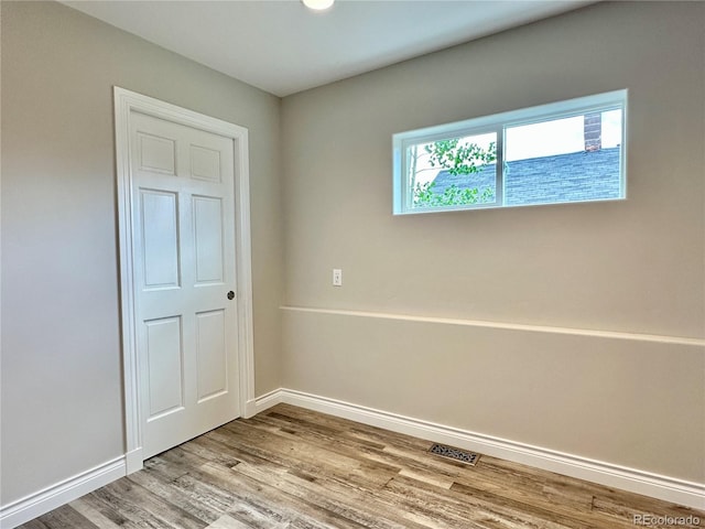 unfurnished bedroom with wood finished floors, visible vents, and baseboards