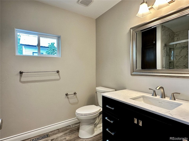 full bath with vanity, wood finished floors, baseboards, a marble finish shower, and toilet