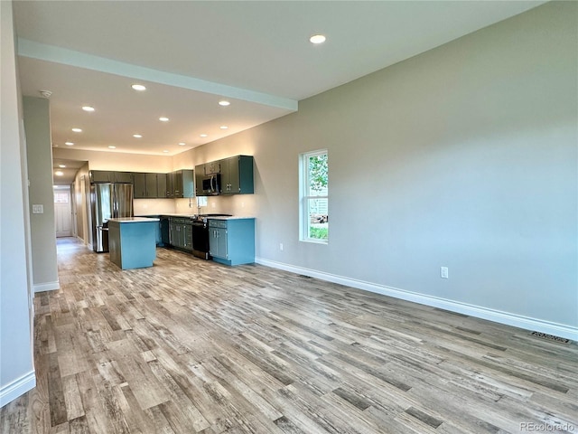 kitchen with baseboards, open floor plan, light wood finished floors, and stainless steel appliances