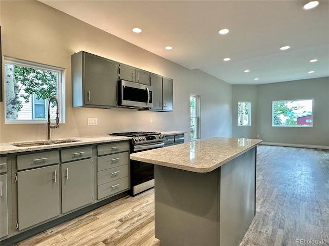 kitchen with a sink, light wood-style flooring, gray cabinets, and stainless steel appliances