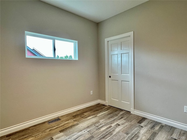 unfurnished bedroom featuring visible vents, baseboards, and wood finished floors