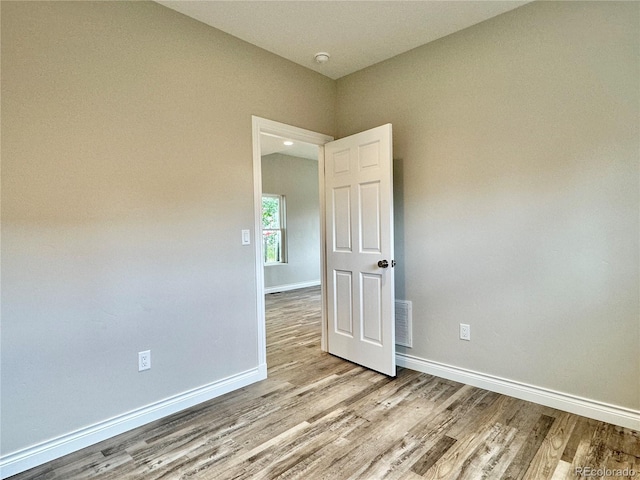 unfurnished room featuring visible vents, wood finished floors, and baseboards