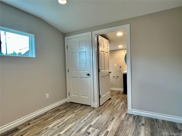 unfurnished bedroom with recessed lighting, wood finished floors, and baseboards