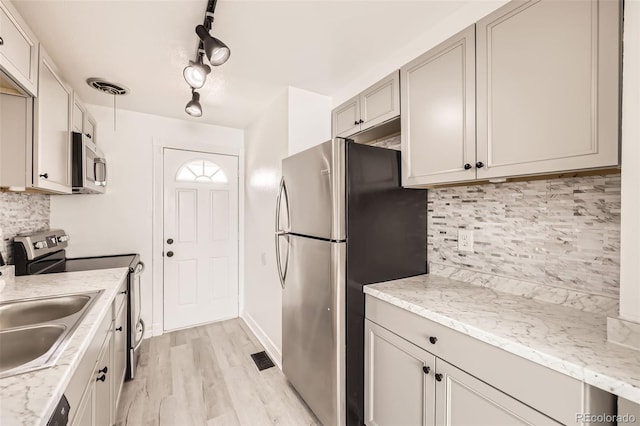 1537 Xenia St, Denver, CO 80220 - kitchen with appliances with stainless steel finishes, decorative backsplash, light wood-style flooring, and a sink