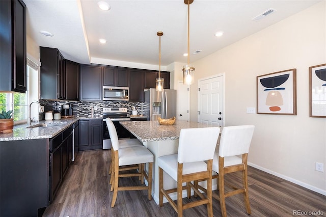 kitchen with a center island, tasteful backsplash, appliances with stainless steel finishes, and dark wood-type flooring