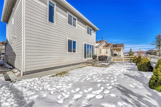 snow covered rear of property featuring a patio area