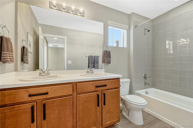 full bathroom featuring tiled shower / bath combo, vanity, wood-type flooring, and toilet